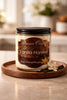 Vanilla Harvest Candle in a glass container on a wooden tray with vanilla pods and flowers.