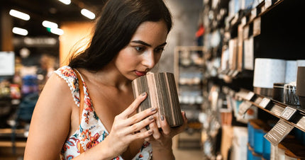A woman smelling a candle in a store while exploring the strongest smelling candles 2026.