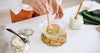 Mixing best coconut wax for candle making in a glass bowl with wooden utensils and natural ingredients.