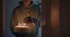 Dark wood, spice, smoke, and fresh fragrance elements styled beside a candle.