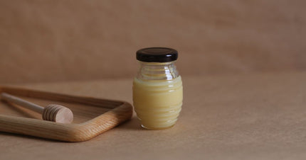 A jar of honey with a wooden dipper, highlighting natural ingredients for pure beeswax candles for clean air.