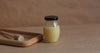A jar of honey with a wooden dipper, highlighting natural ingredients for pure beeswax candles for clean air.