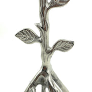 Silver-toned tree-branch candle holder with raised leaf details and a sculptural root-like base.