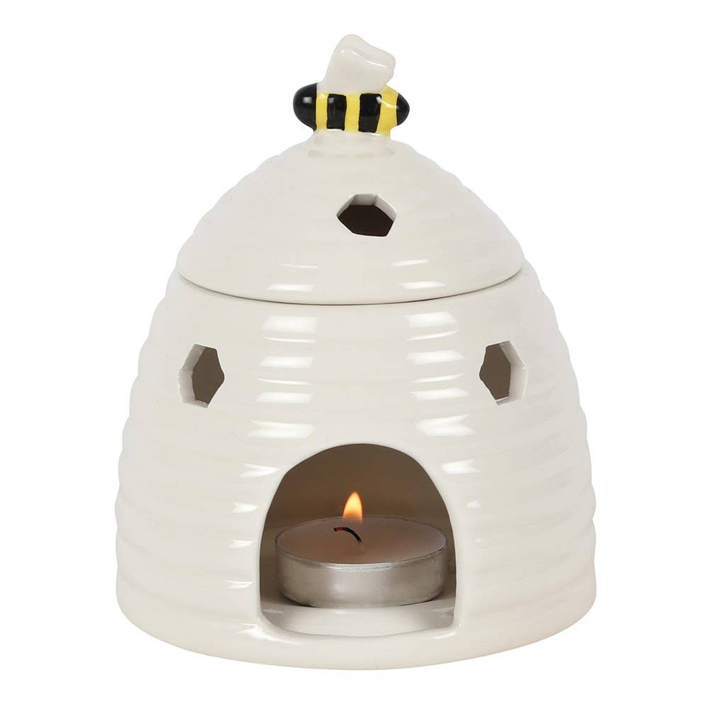 White ceramic beehive-shaped tealight warmer with hexagonal cutouts, bee figurine lid knob with black-and-yellow stripes.