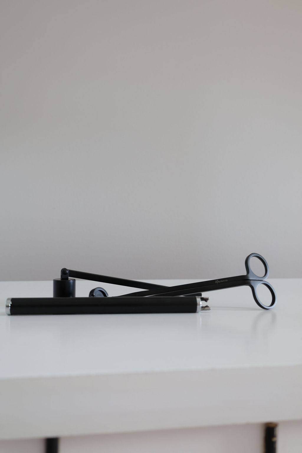 Candle Accessories including a black candle snuffer and wicks trimmer on a white surface for candle care.