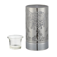 Silver cylindrical metal wax warmer with laser-cut honeybee, hexagon and floral pattern; clear glass cup positioned left