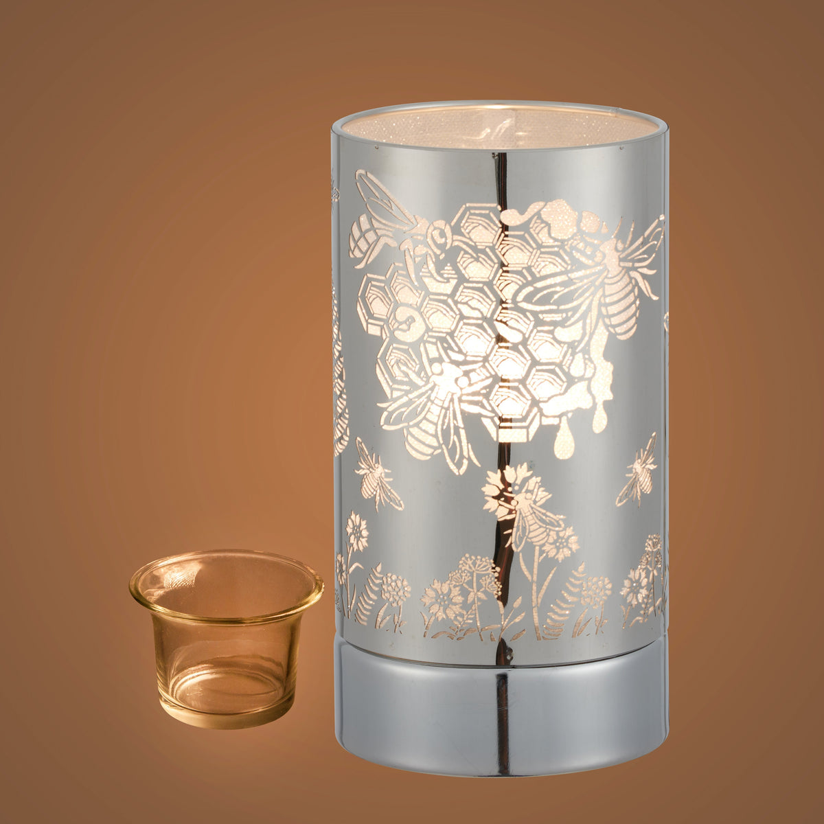 Silver cylindrical metal wax warmer with laser-cut honeybee and honeycomb pattern lit from inside.