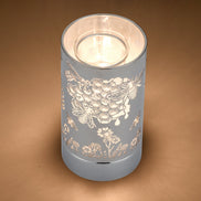 Silver cylindrical wax warmer with cutout honeybee, honeycomb and floral pattern.