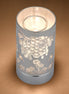 Silver cylindrical wax warmer with cutout honeybee, honeycomb and floral pattern.