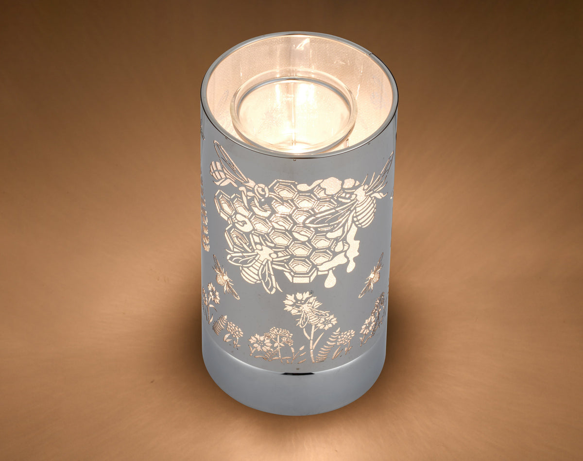Silver cylindrical wax warmer with cutout honeybee, honeycomb and floral pattern.