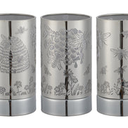 Three cylindrical silver metal wax warmers shown side-by-side with laser-cut honeybee, hive, honeycomb and floral patterns.