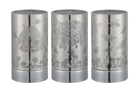 Three cylindrical silver metal wax warmers shown side-by-side with laser-cut honeybee, hive, honeycomb and floral patterns.