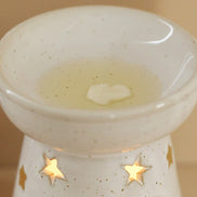 Starry wax melt ceramic warmer with star cut-outs and wax melting in the dish.