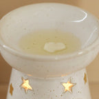 Starry wax melt ceramic warmer with star cut-outs and wax melting in the dish.