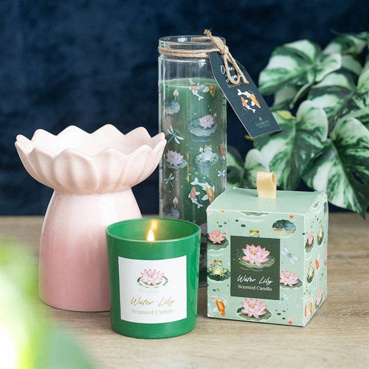 Pink lotus-shaped ceramic oil burner beside a lit green candle labeled 