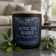 Alpine Tea Reserve candle in a dark glass jar with a wood lid, styled with evergreen sprigs in a light room.