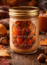 Autumn Harvest Candle in a jar with a golden lid, surrounded by autumn leaves and pumpkins.