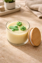 Bamboo Coconut Candle in a glass jar with green succulent decor on top.