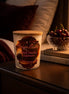 Black Cherry Cashmere Candle displayed on a nightstand with cherries and cozy decor.