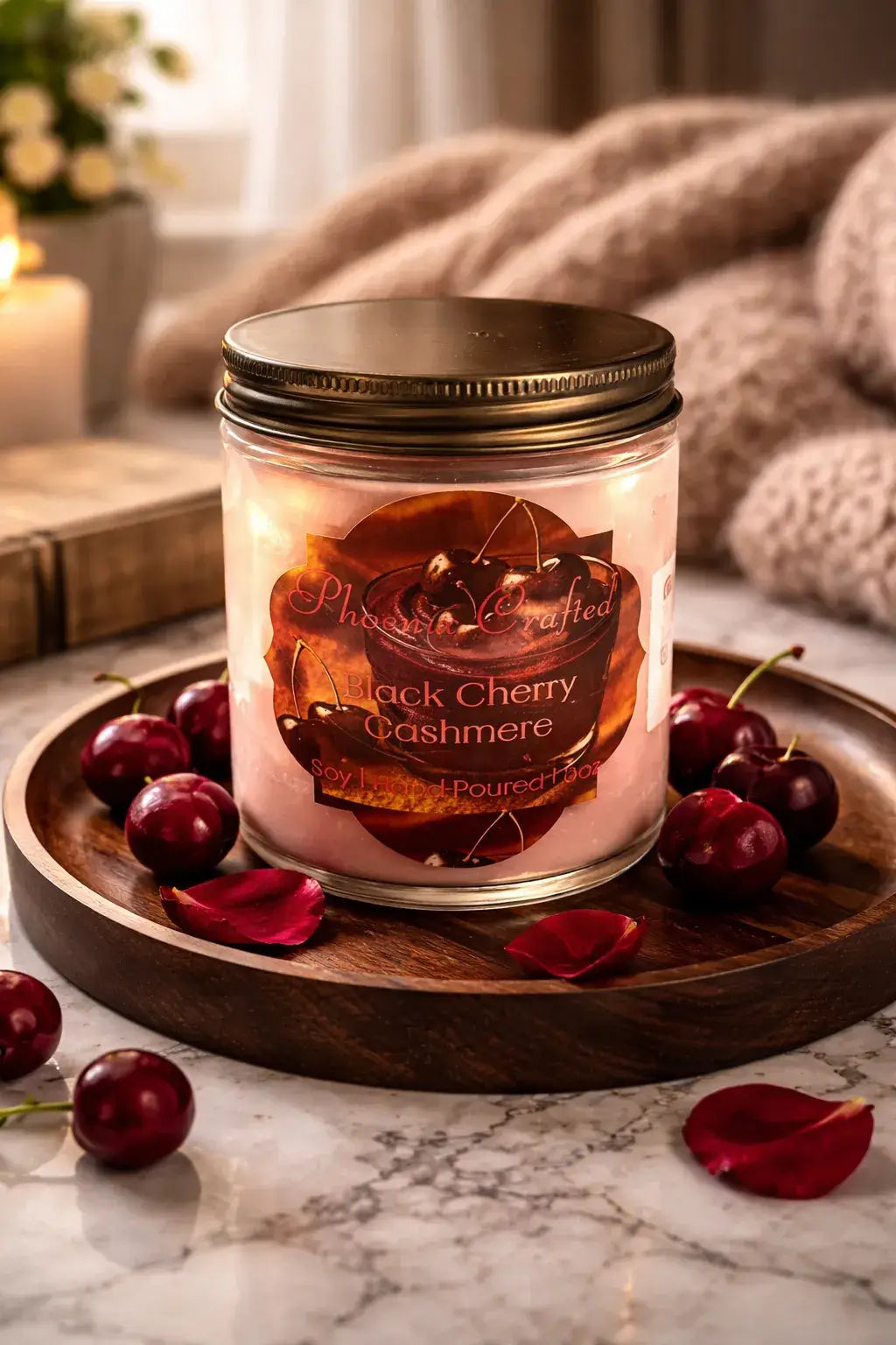 Black Cherry Cashmere Candle in a glass jar on a wooden tray with cherries and rose petals, perfect for cozy atmospheres.