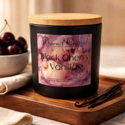 Matte black jar candle with light wood lid and purple floral label reading 'Phoenix Crafted Black Cherry Vanilla'.