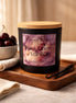 Matte black jar candle with light wood lid and purple floral label reading 'Phoenix Crafted Black Cherry Vanilla'.