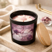 Black matte jar with pink wax topped by a white daisy flower and visible wick, labeled Phoenix Crafted Cherry Vanilla.