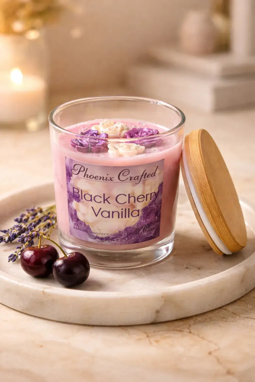 Clear jar of Black Cherry Vanilla Candle with floral design and wooden lid, surrounded by lavender and cherries.