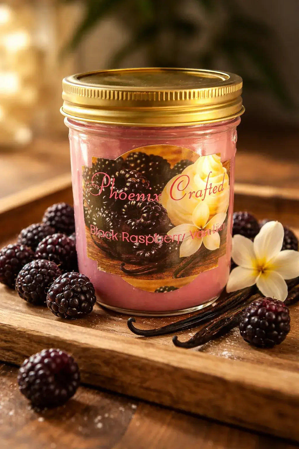 Black Raspberry Vanilla Candle in a jar surrounded by blackberries and vanilla pods on a wooden tray.