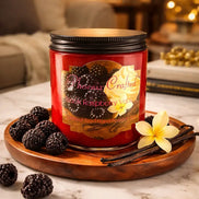 Black Raspberry Vanilla Candle on a wooden tray surrounded by black raspberries and vanilla flowers.