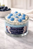 Blueberry Cream Pie Candle in a glass jar with blue and cream frosting decoration.
