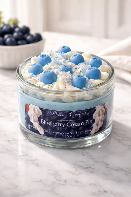 Blueberry Cream Pie Candle in a glass jar with blue and cream frosting decoration.