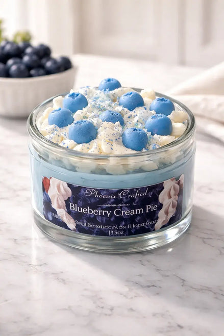 Blueberry Cream Pie Candle in a glass jar with blue and cream frosting decoration.