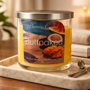 Butt Naked candle in a clear lidded glass jar on a marble tray with a mango-and-coconut label.