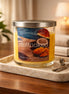 Butt Naked candle in a clear lidded glass jar on a marble tray with a mango-and-coconut label.