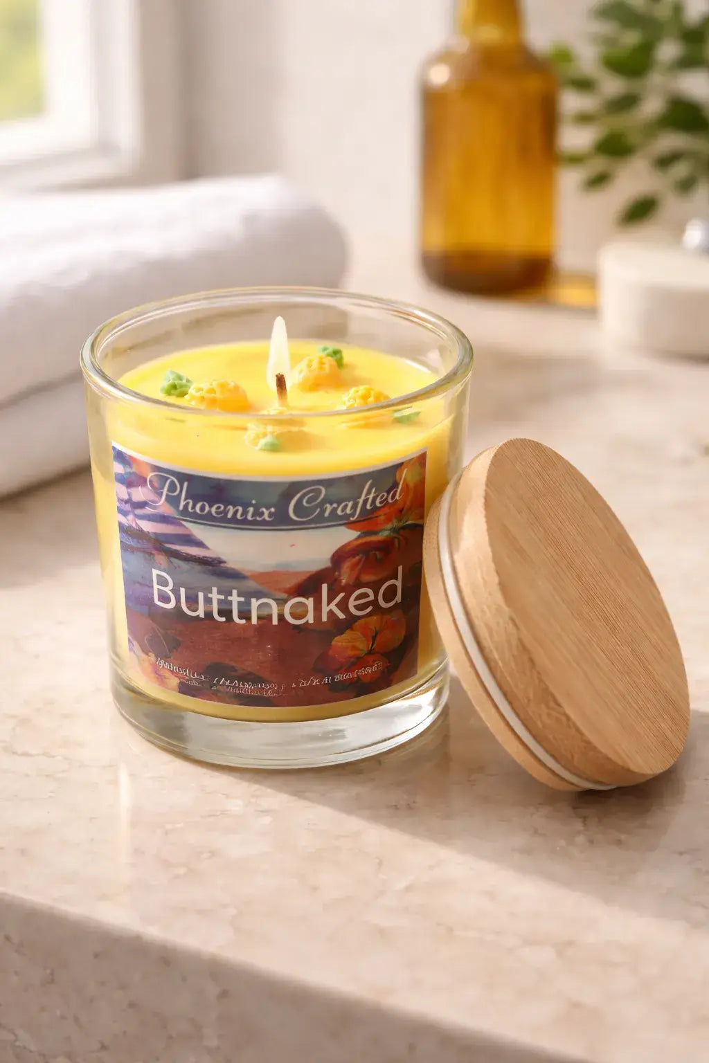 Buttnaked Candle in a glass jar with a wooden lid on a stone countertop, featuring tropical fruit scents.