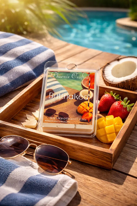 Butt Naked wax melt on a wooden tray with tropical fruits, sunglasses, and a beach towel beside a swimming pool.
