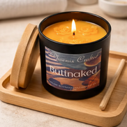 Butt Naked candle by Phoenix Crafted on a wooden tray with a lit wick.