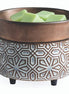 Bronze-and-cream ceramic wax warmer with a raised geometric pattern and a top dish holding pale green wax cubes.