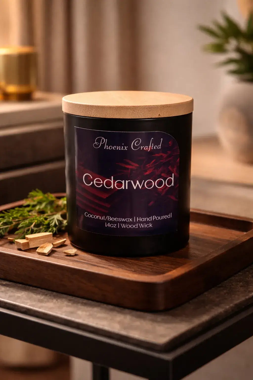 Black glass Cedarwood candle with a pale wooden lid on a rectangular wood tray with wood chips and greenery.