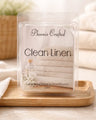 Clean Linen Wax Melts packaged in clear container with folded towels and floral accents.