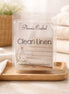 Clean Linen Wax Melts packaged in clear container with folded towels and floral accents.