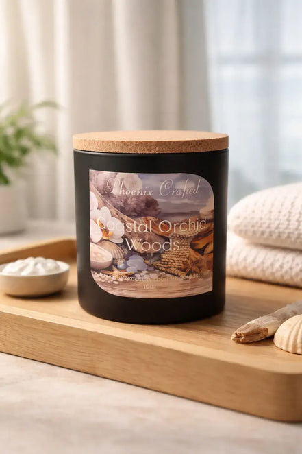 Coastal Orchid Woods Candle displayed on a wooden tray with seashells and a soft towel in a serene setting.