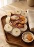 Wrapped pack of unscented tealights with short wood wicks on a wooden tray beside a honeycomb and coconut-themed card.