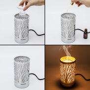Silver cylindrical wax warmer with tree-branch cutout pattern and black power cord; shown with a clear plastic cup, dropper and bottle.