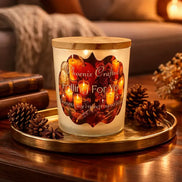 Falling For You frosted glass jar candle with wooden lid and Phoenix Crafted autumn label, on a round brass tray surrounded by pinecones.