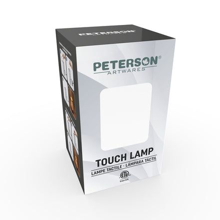 Tall white-and-gray rectangular product box with black top, teal 'PETERSON ARTWARES' logo, blank front window cutout and bold 'TOUCH LAMP' text