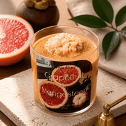 Grapefruit & Mangosteen Candle in a glass jar with grapefruit slice and mangosteen fruit on a wooden table.
