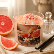 Grapefruit & Vanilla Candle in a glass jar with pink toppings, surrounded by grapefruit slices and decorative items.