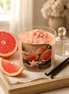 Grapefruit & Vanilla Candle in a glass jar with pink toppings, surrounded by grapefruit slices and decorative items.